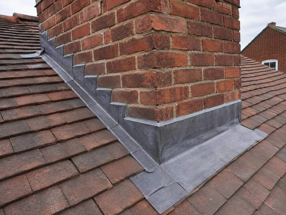 New lead flashing around a chimney stack, chased into the brickwork and dressed over the tiles